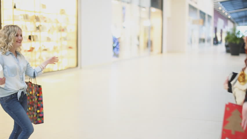 Two women meet and embrace in the mall