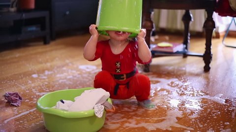 Cute baby toddler playing with spilled water on the floor at home
