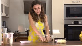 Beautiful young woman making dessert at home. 4K steadicam video