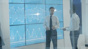 4K Business team in modern office, looking at video wall with graphs and data (UK-Oct 2016)