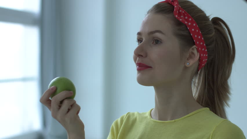 Portrait of young pin up woman eating healthy green apple
