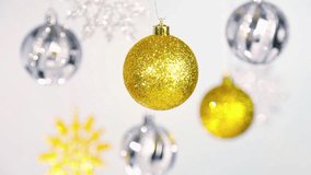 Beautiful Christmas and New Year blurry silver and golden shining balls and snowflakes hanging on silver ropes over white background. Real time full hd video footage