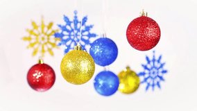 Christmas colorful background. Close up of beautiful New Year blurry golden, red, blue round shining balls and snowflakes hanging on silver ropes isolated on white. Real time full hd video footage