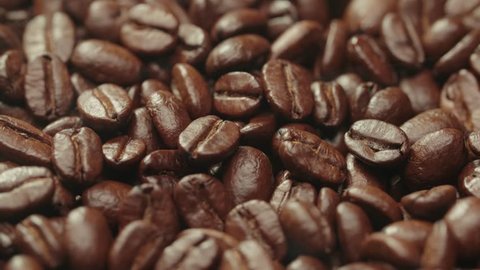 beautiful background of roasted steaming coffee beans which rotate in slow motion
