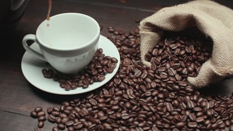 pouring a Cup of hot coffee and roasted coffee beans on the table, slow motion