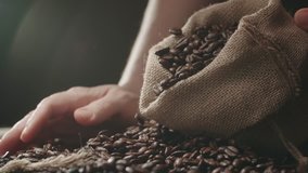 human hands the farmer to touch high-quality coffee beans to scatter, bag jute, slow motion
