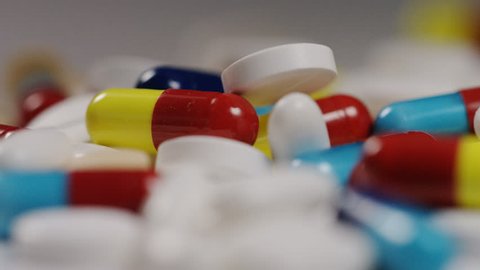4K Colourful mix of different medication falling on white surface