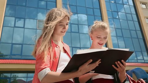 Two young business girls working with papers on background of office building.