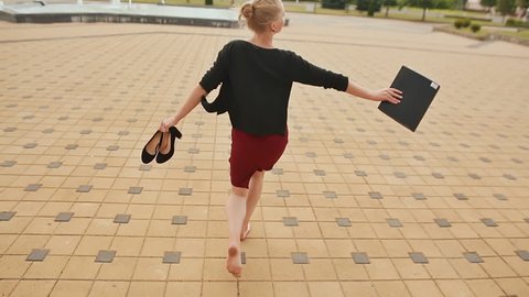 Beautiful girl businesswoman barefoot with shoes and a folder in his hands after a hard day of skipping.