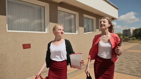 Two beautiful and happy girls are students at the University notes. Front view.