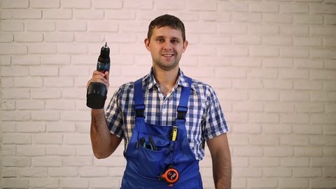 A man with a screwdriver.  Worker repairman, builder of the working suit. Master power tools. Man holding a screwdriver in his hand. Worker with screwdriver showing thumb up.