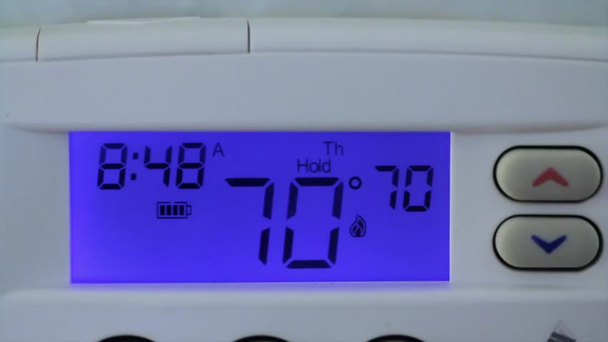 Turning down the temperature on a thermostat to save energy