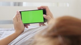 Female in modern white bedroom with green screen display smart phone 4K 2160p 30fps UltraHD video - Zooming out from woman at home with greenscreen tablet device 3840X2160 UHD footage