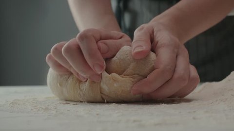 Baker kneading dough in flour on table, slow motion