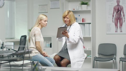 Mid Adult Female Doctor Shows Something on a Tablet to Her Young Female Patient. Both Smile and Feel Relaxed.  