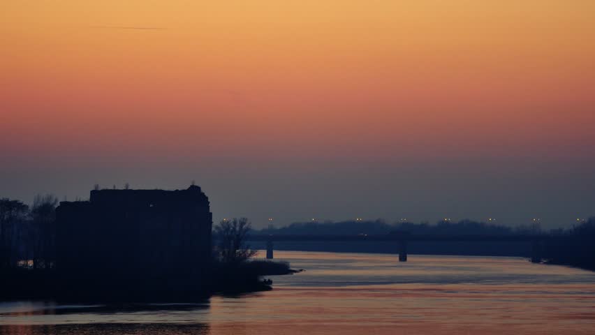 Sunset landscape of river with bridge on the horizon