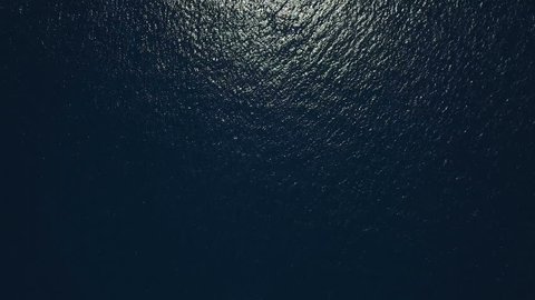 Aerial - Top down view of a deep blue sea rippling water surface reflecting the sunlight 
