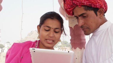 Rajasthani couple working learning teaching sharing on a tablet wearing pink sari and red turban in India  วิดีโอสต็อก