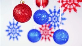 Christmas and New Year blurry blue and red bright color shining beautiful Xmas balls and snowflakes hanging on silver ropes at white background. Real time full hd video footage