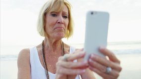 Active Caucasian senior female smartphone technology selfie video diary leisure health care smiling beach 