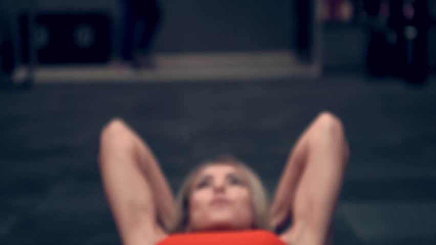 Muscular woman in a red top working out in the gym lifting weights