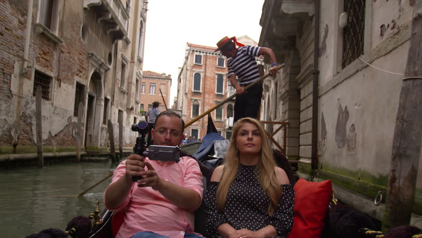 Beautiful lovers couple in Venice on Gondola ride. Romance shot in boat with a gondolier on the background. Happy together on travel vacation holiday in Venice, Italy