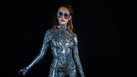 sexy cool woman posing and dancing in a metallic silver catsuit in a disco setting