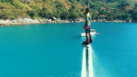 Aerial: Man standing over the water on flyboard.