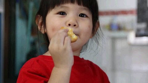 Asian cute little child girl have fun eating cookies