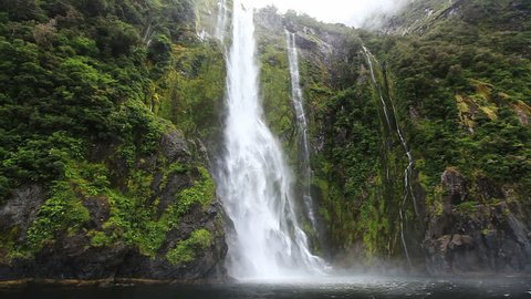 Close approach to waterfall by boat, Milford Sound Fjord. South Island, New Zealand.