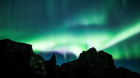 Glowing aurora borealis over volcanic rock formations time lapse 4k