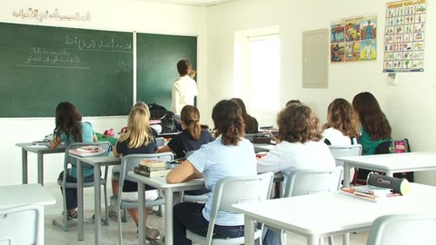 Dubai, UAE - circa 2013 - Scene of young primary schoolgirls listening while the teacher is at the blackboard teaching an Arabic language grammar class, in a Dubai primary school. (Dubai, UAE-2013)