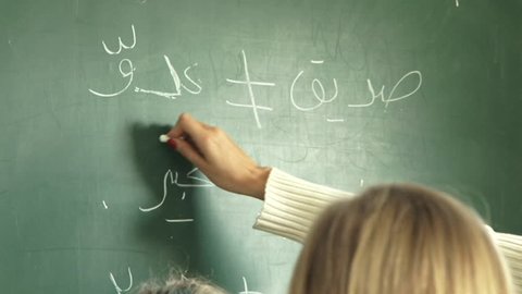Tilt-down from blackboard to expat primary schoolgirls listening while the teacher is at the blackboard teaching an Arabic language grammar class, in a Dubai primary school. (Dubai, UAE-2013)