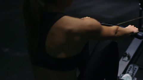Beautiful girl athlete doing rowing crossfit exercises at the gym. Closeup hand