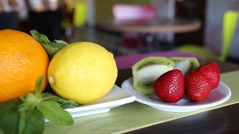 fresh fruit plate on the table. orange, lemon, kiwi, strawberry mint leaves. Slider shot