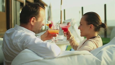 Young happy couple drinking exotic cocktails outdoors