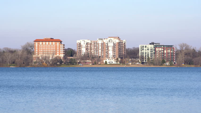 4K exterior day dx establishing shot of waterfront apartment buildings along large lake in Minneapolis Minnesota. Expensive midwest real estate development population growth.