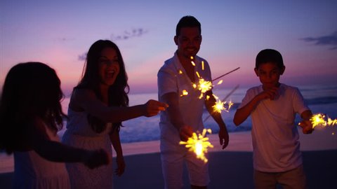 Silhouette Spanish family parents children leisure tourism sparklers party childhood memories beach sunset dusk RED DRAGON