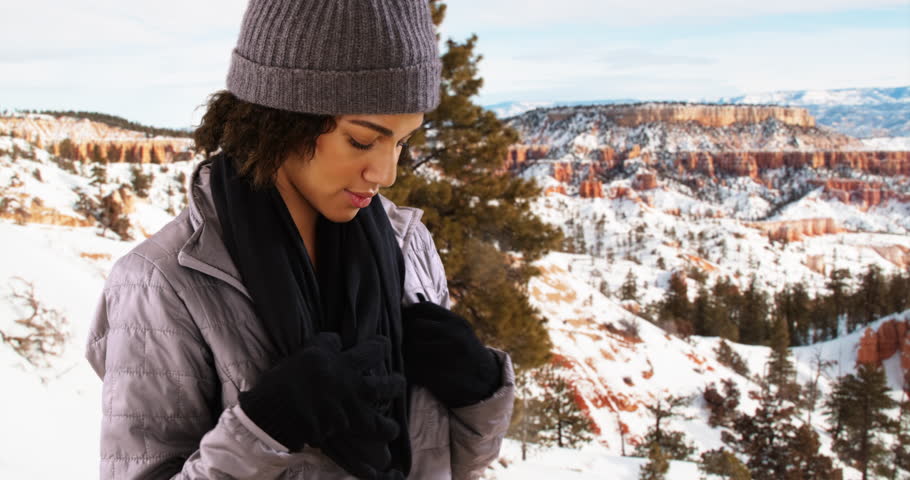 Black woman zipping up jack in the cold. Portrait of single black girl standing in the snow, nature background.