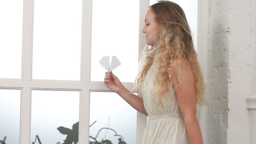 Pretty young girl holding an airplane made of paper