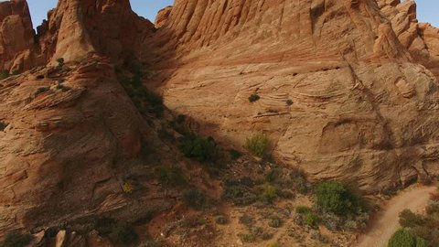 Ascending drone footage of red rock in Moab, with valley in the background.