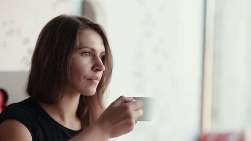 Close-up of a pretty brunette womans face having a cup of coffee or tea. She talks, smiles, has good time. | Shutterstock HD Video #22123978