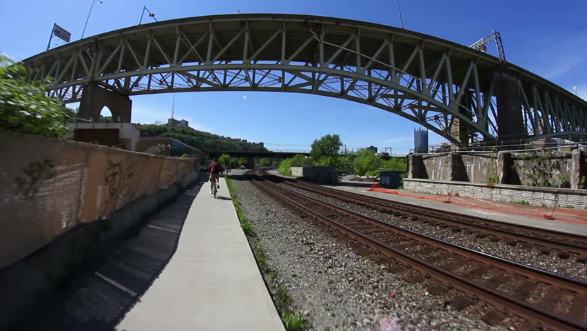 A man rides his bike on a Pittsburgh bike trail under the Liberty Bridge.