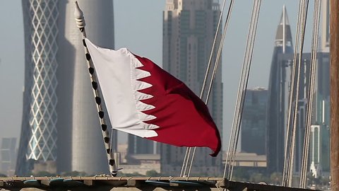 flag of Qatar sea side on a dhow cruise boat, with Doha towers in the background