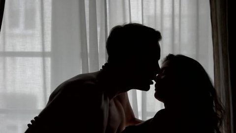 Kiss of couple in slow-mo. Silhouettes of man and woman. Nothing can break us apart. Passion and warmth of heart.