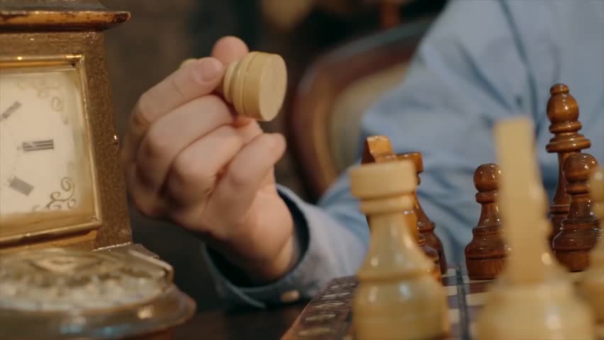 Hand moving a knight chess piece on wooden chessboard