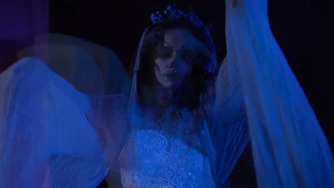 Horror scene from the film with dead girl in white wedding dress and veil. Creepy visual hallucination in the form of changing images of young girl with skull mask on her face.