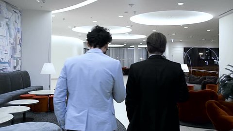 Two businessmen are going through a hall of the business hotel. Back view. Slow motion.