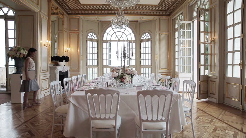 Woman catering manager or wedding planner walks around festive table set decorated for wedding banquet celebration in luxury room dining hall interior. Decoration of events stylish table arrangement 