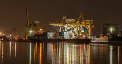 Night to day while working crane bridge lifting container cargo to freight ship at shipyard in morning ,Bangkok Thailand

